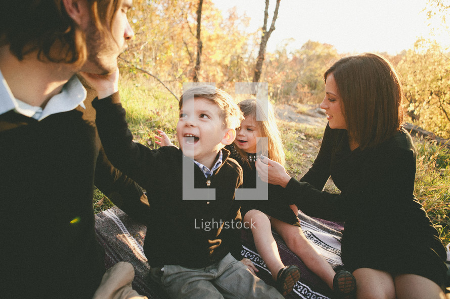 family sitting on a blanket in the grass 
