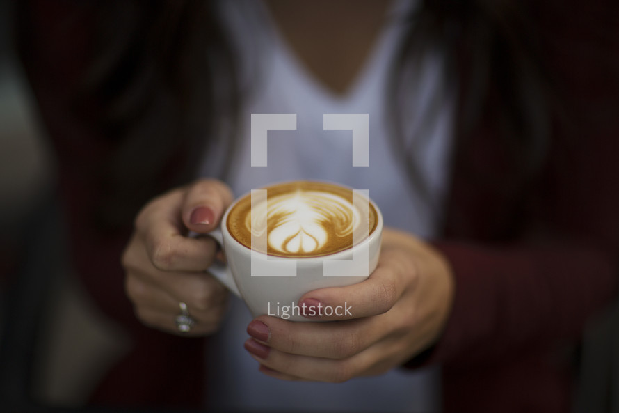 a young woman holding a cup of coffee with creamer 