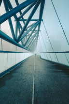 people crossing a bridge in fog 