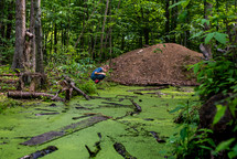 boy exploring a green pond 