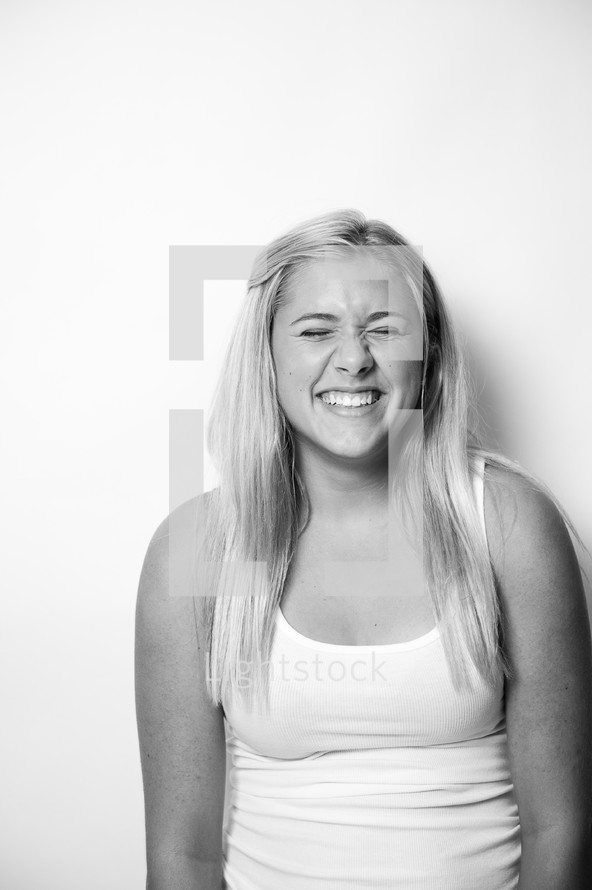 portrait of a blonde teen girl with closed eyes laughing 