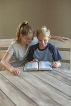 a brother and sister reading a Bible 