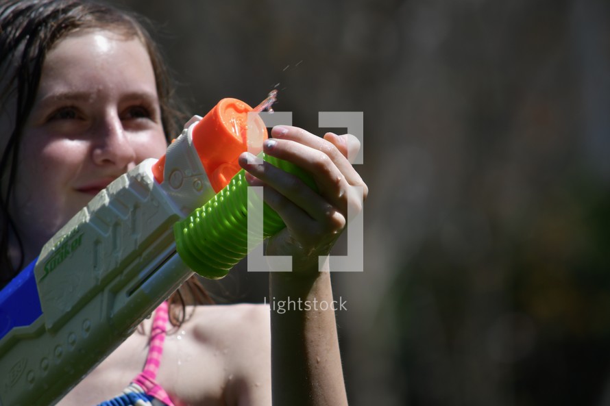 girl with a water gun in summer with copy space 