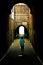 man walking down an alley and brick tunnel 