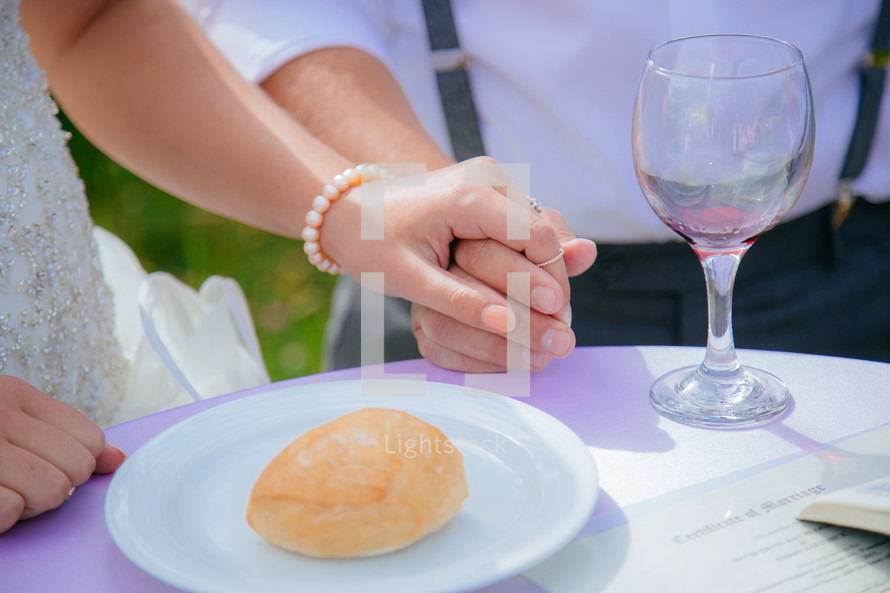 bride and groom holding hands in front of bread and wine 