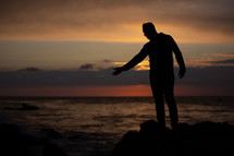 silhouette of a man on a shore at sunset 