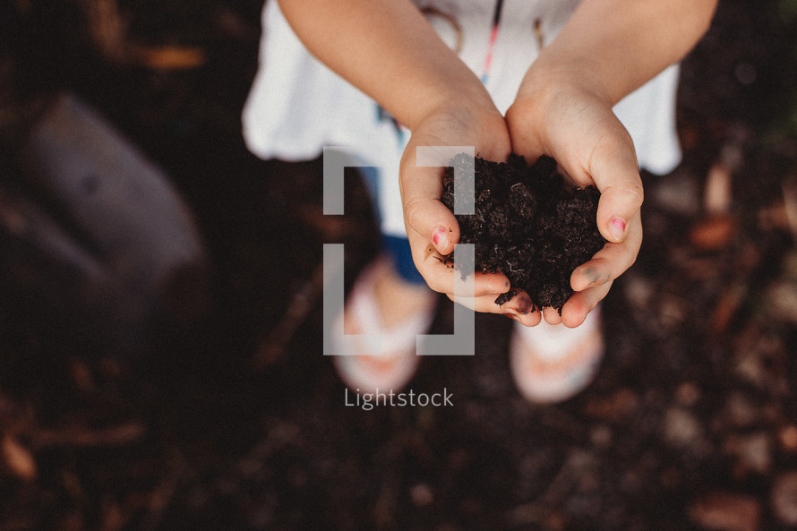 child with cupped hands with soil 