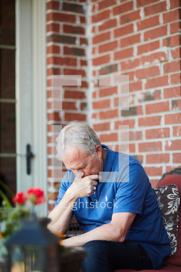 a man sitting on a porch with head down