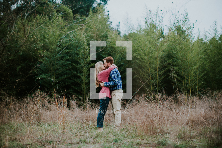 a couple kissing standing in a field 