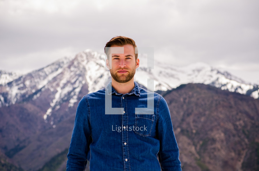 a man standing in front of a snow covered mountain peak 