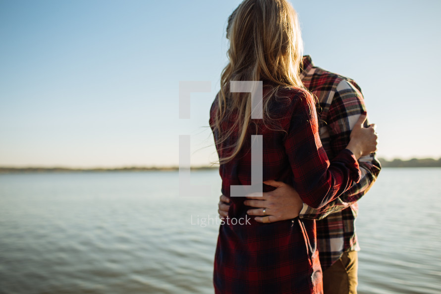 a couple embracing by a lake 