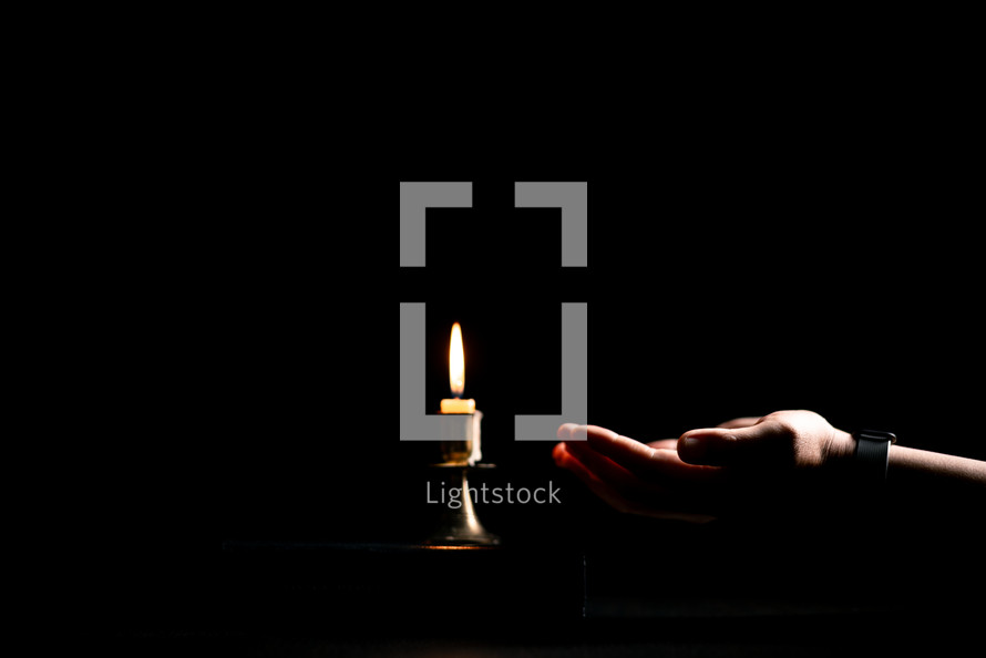 Bible and candlelight with praying hands