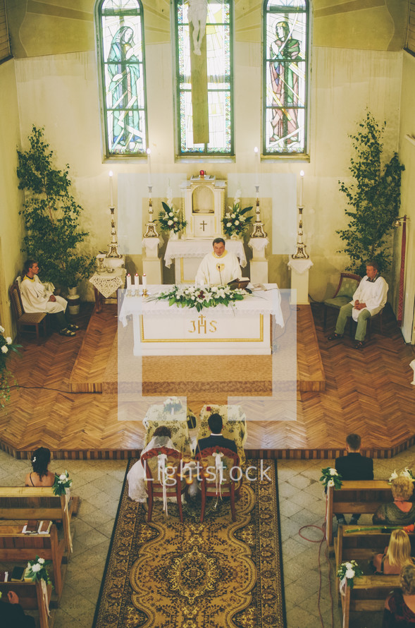 bride and groom sitting in chairs in front of the altar 