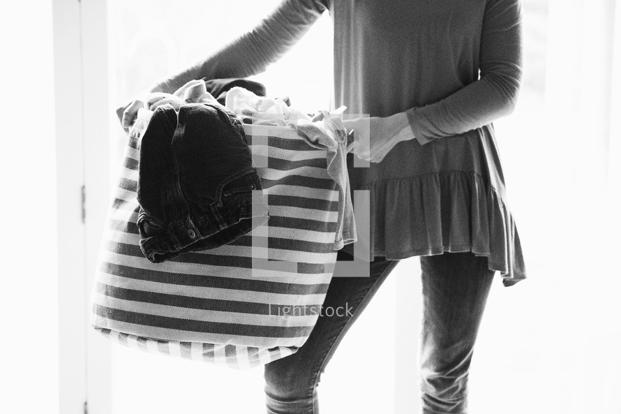 a woman holding a basket of dirty laundry 