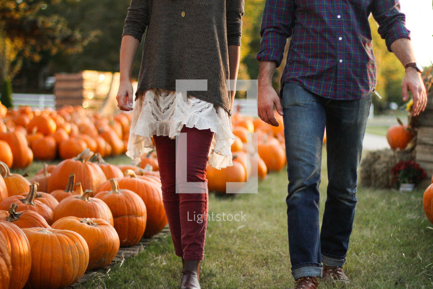 a couple walking through a pumpkin patch 