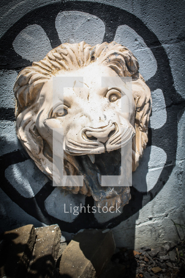 Engraving statue of a lion's head hanging off a wall.