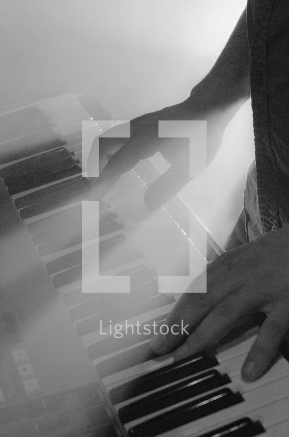 stage lights on a hands playing a keyboard 