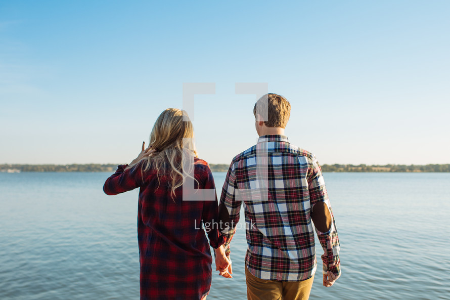 a couple holding hands on a dock 