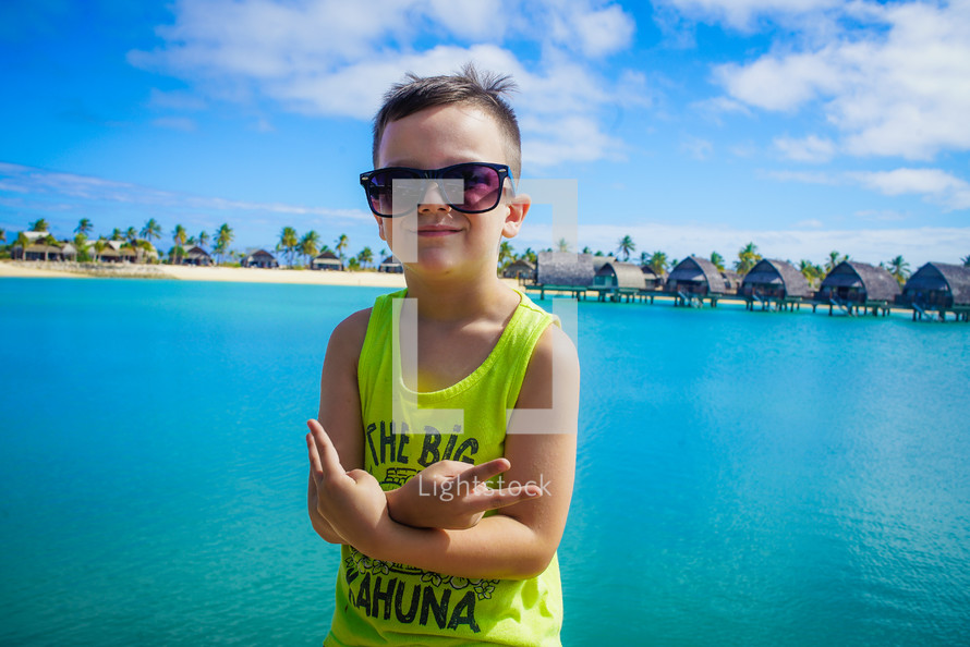 a boy with open arms standing in front of tropical vacation property 