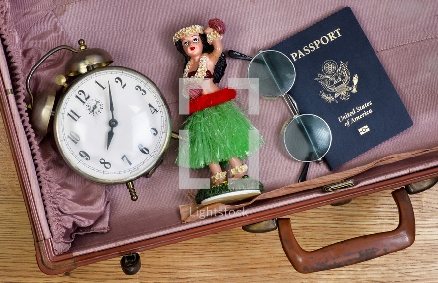 alram clock, passport, Hawaiian dancer, and glasses in a suitcase 