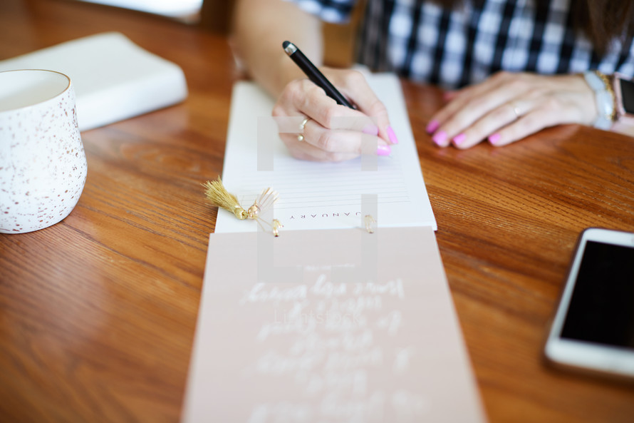a woman sitting at a desk making a list 