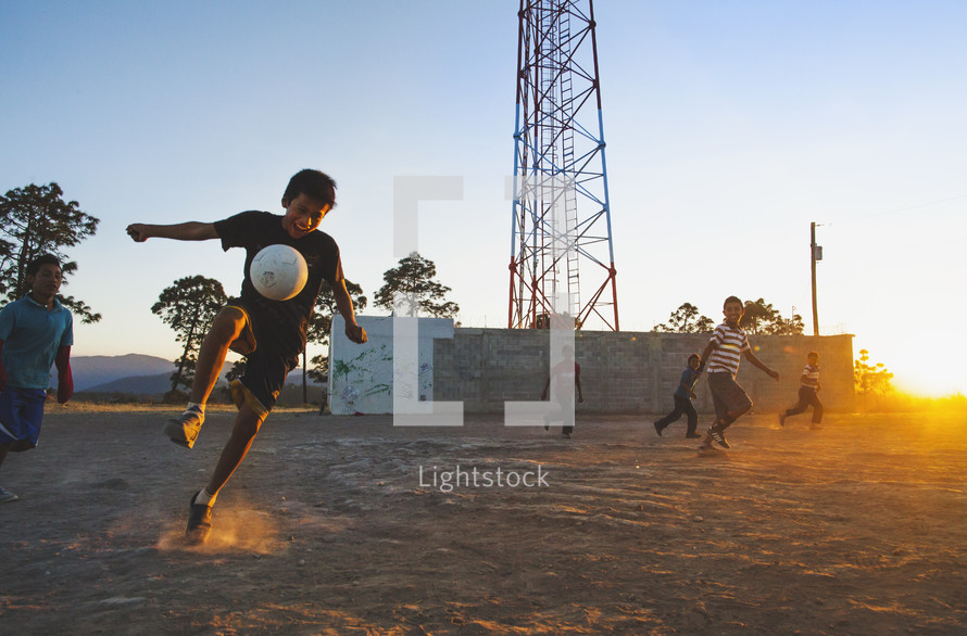children playing soccer in the dirt 