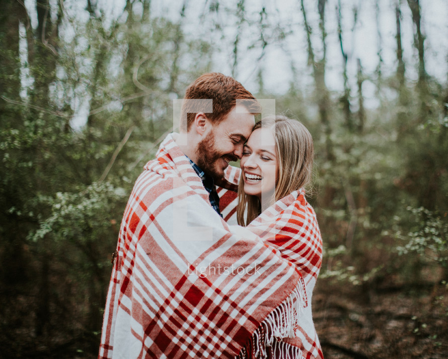 a couple wrapped up in a plaid blanket 