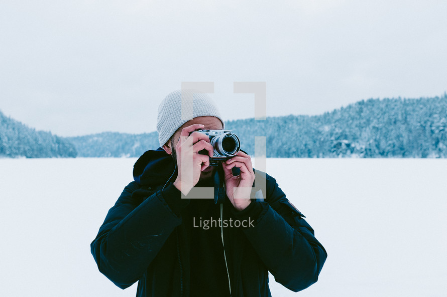 a man standing in snow taking pictures with a camera 