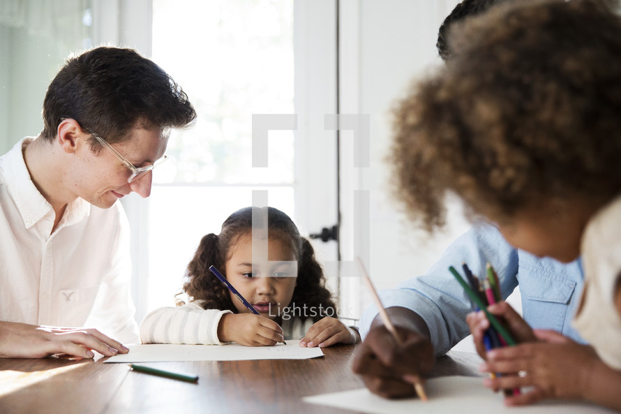 a family coloring together at the kitchen table.