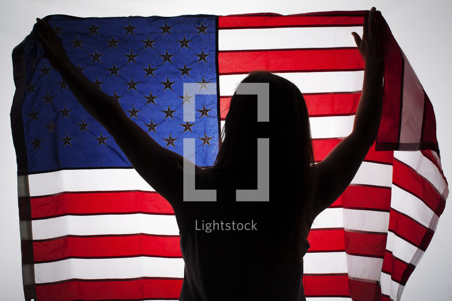 silhouette of a woman holding up an American flag.