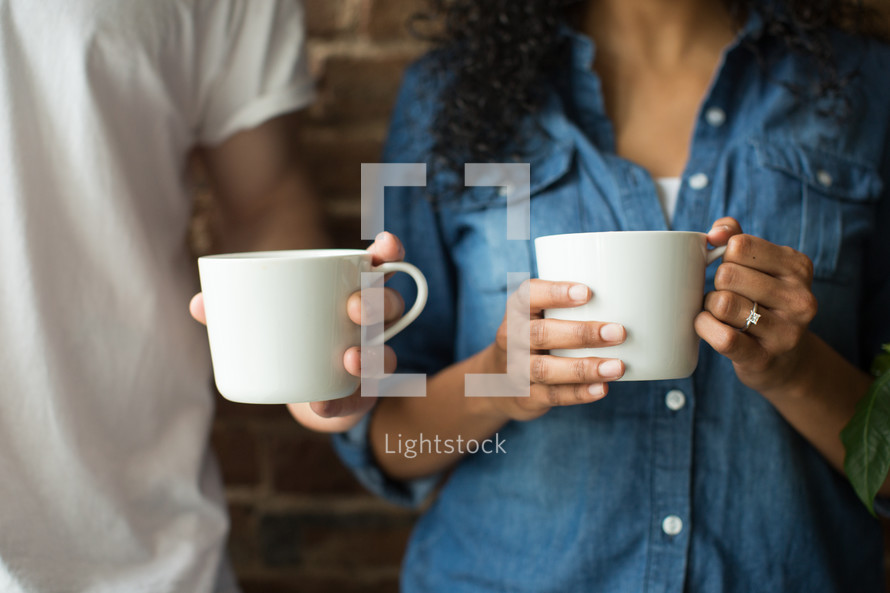 a couple holding coffee mugs 
