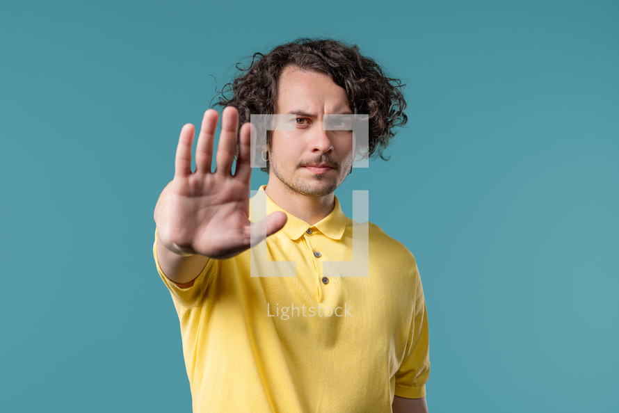 Serious american man showing rejecting gesture by stop finger sign. Dont play with me. Guy isolated on blue background. High quality