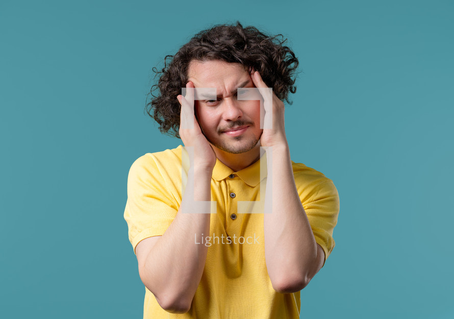 Young man having headache, blood pressure, blue studio portrait. Guy putting hands on head, isolated on violet background. Concept of problems, medicine, illness. High quality