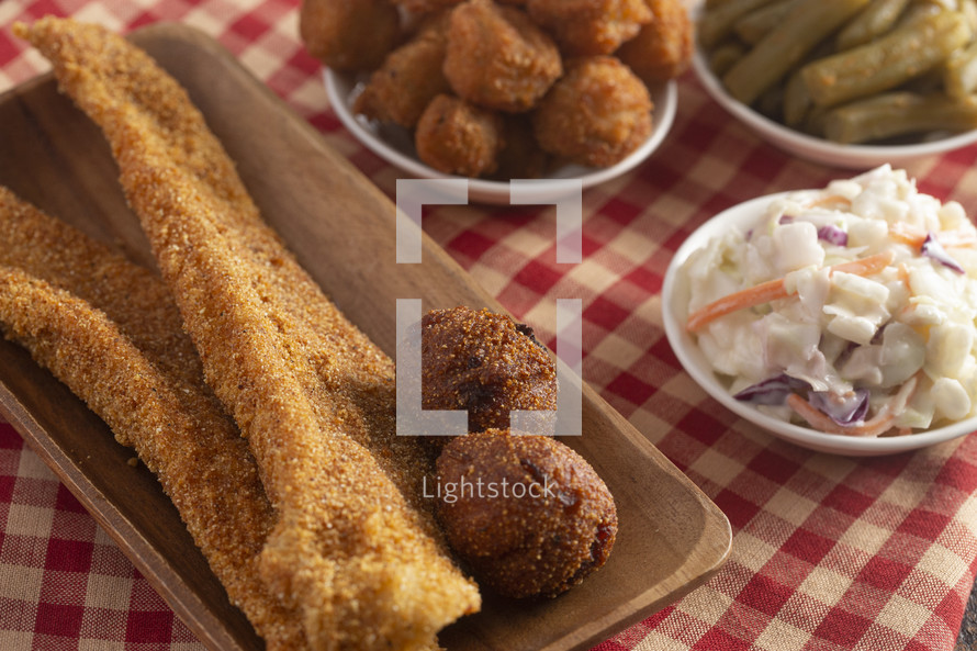 Breaded and Fried Fillets of Fish with Hushpuppies on a Rustic Wooden Table