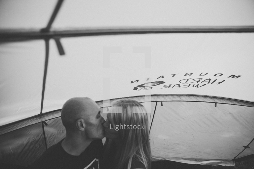 A couple kissing in a tent. 