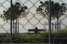 a man sitting on a bench looking out at the water 