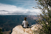 woman sitting at the edge of a canyon landscape 
