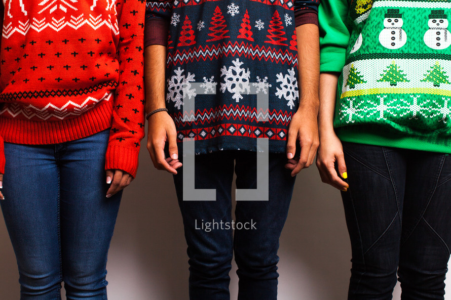 friends standing in ugly Christmas sweaters 