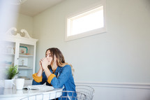 a woman reading a Bible sitting at a kitchen table and praying 