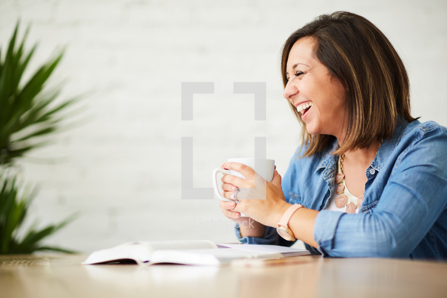 a woman holding a coffee mug and reading a Bible 