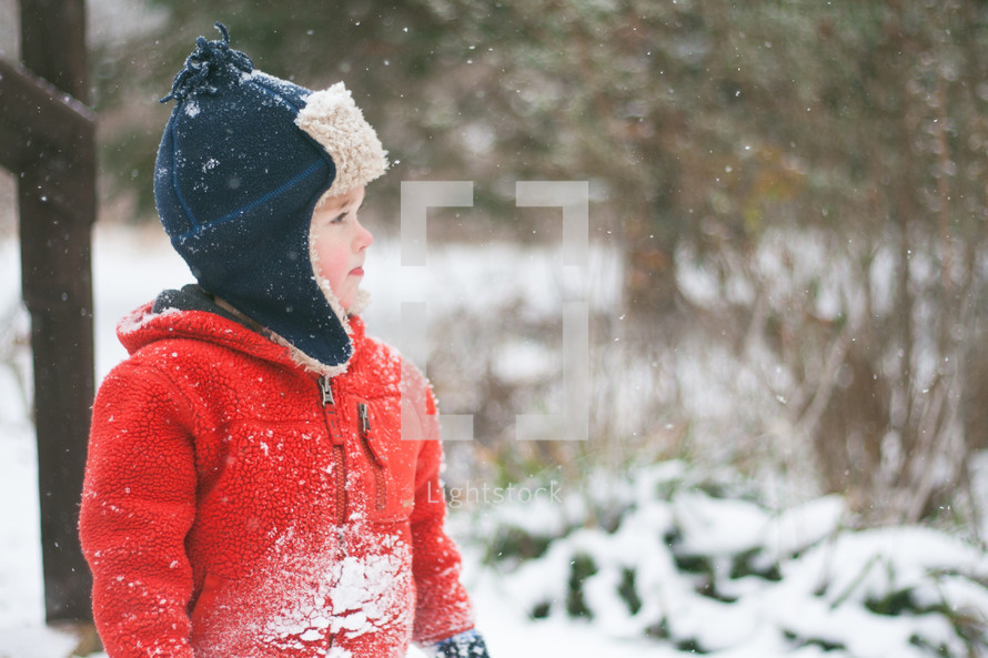 a boy child standing outdoors in the snow 