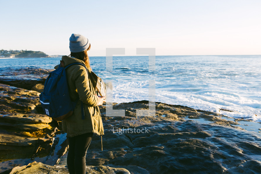 woman standing on rocks looking out at the ocean 