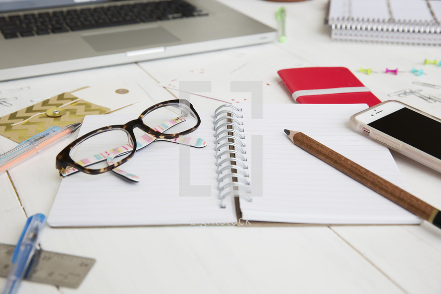 a pencil and reading glasses on an open notebook 