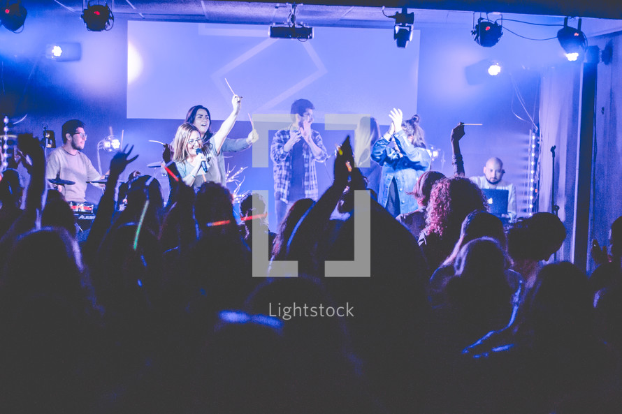 people holding a microphone and singing during a worship service 