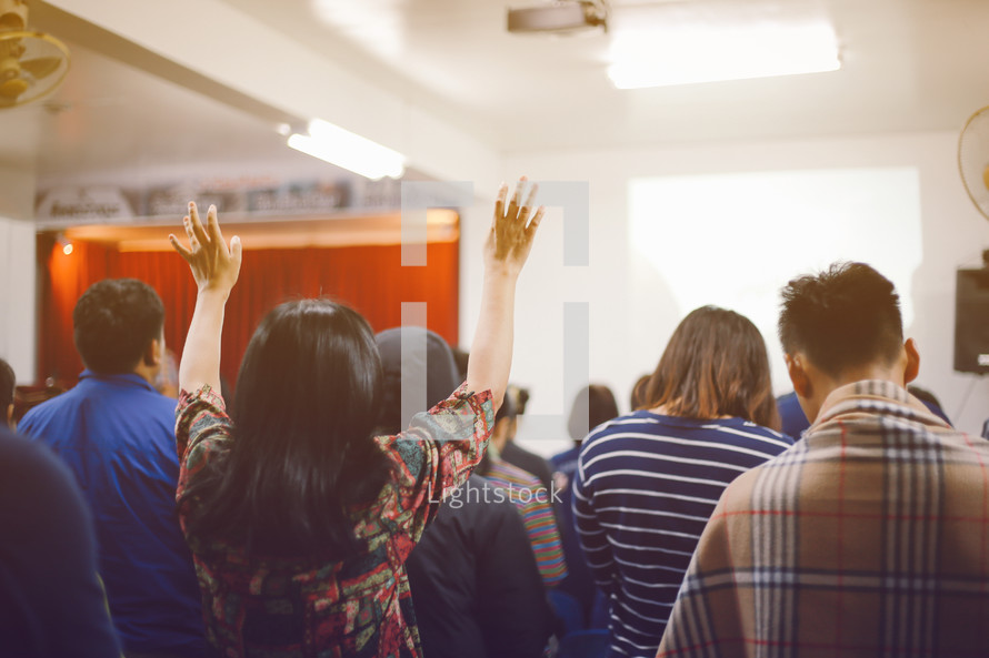 people standing with hands raised at a worship service 