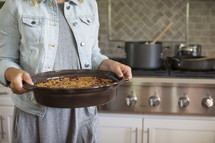 a woman holding a casserole 