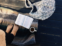 woman standing on a blanket outdoors with a Bible 