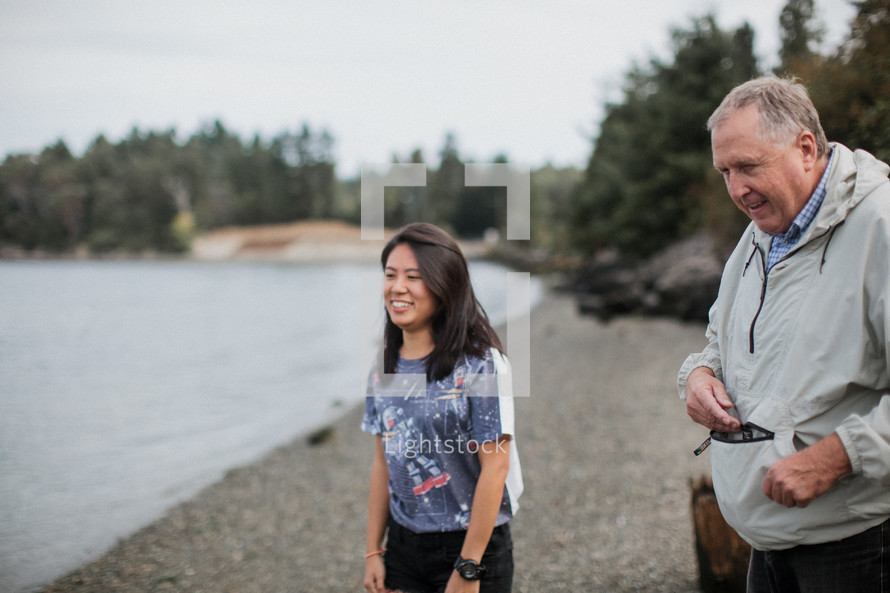 a man and a woman standing on a shore before an outdoor baptism 