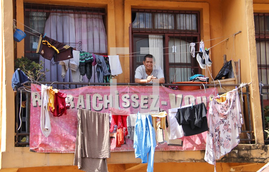 a man and laundry hanging on a clothesline off a balcony 