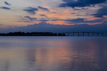 a bridge across water at sunset 